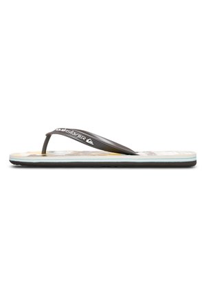Tongs en caoutchouc noir avec une large bride entre les orteils. La semelle présente un motif léger en beige et jaune, avec une accentuation bleue contrastante.