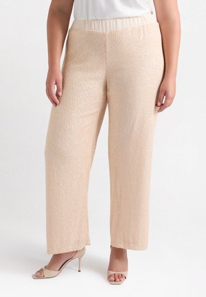 Pantalones de pierna ancha en color beige, adornados con lentejuelas y con una textura acanalada, que cuentan con una cinturilla elástica, combinados con unos tacones de punta abierta en tonos neutros.