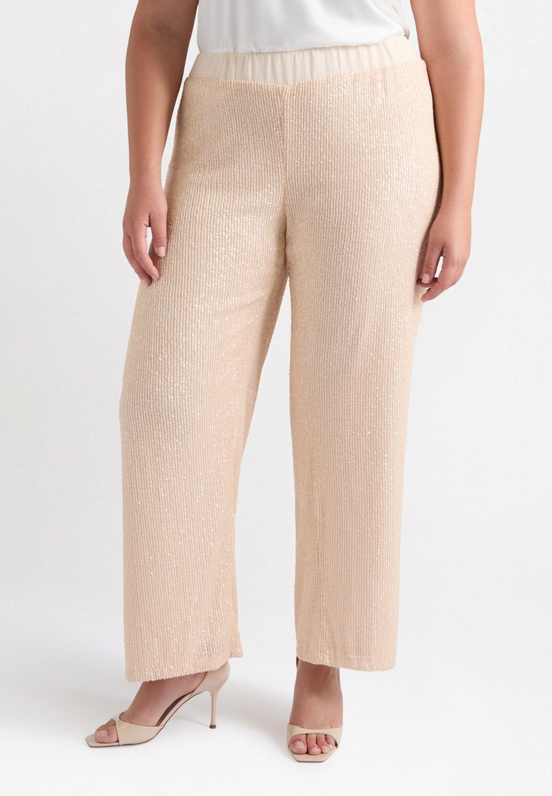 Pantaloni a gamba larga beige decorati con paillettes, con una texture a costine, caratterizzati da una vita elastica, abbinati a tacchi aperti in tonalità neutre.