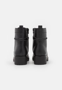 Botas de tobillo de cuero negro con un acabado texturizado, que cuentan con cierre de cremallera, tira para el talón y una suela de goma gruesa y estriada.