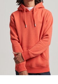 Sudadera naranja con bolsillo delantero, capucha con cordón y puños acanalados. Presenta bordado del logo en el pecho. Textura suave.