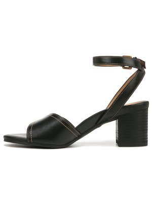 Sandale à talon en cuir noir avec un talon bloc épais et texturé. Dotée d'une sangle de cheville et d'un design à bout ouvert avec des brides croisées.