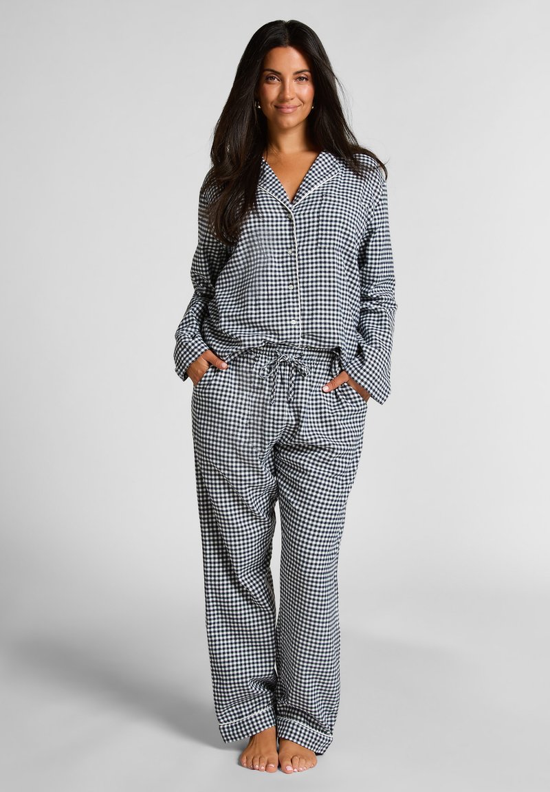 Zwart-wit geblokt pyjama-set met een knopsluiting bovenstuk en broek met trekkoord, gemaakt van zachte stof en met een relaxte pasvorm.