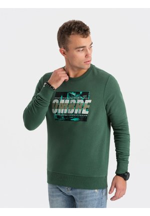 Sudadera verde hecha de material suave, con un estampado gráfico que incluye el texto "OMBRE". Las mangas largas y los puños acanalados completan el diseño.