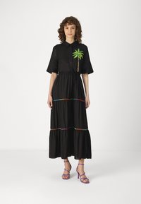 Rochie maxi neagră cu mâneci scurte, având broderie cu palmier și cusături orizontale colorate. Purtați-o cu sandale cu toc de unghii purpurii.