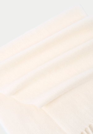 Tissu doux de couleur crème avec un bord plié et une texture côtelée subtile, présenté en gros plan avec un éclairage doux.