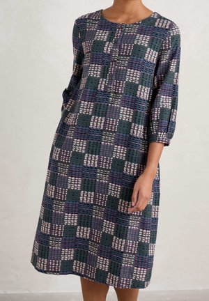 Robe à manches trois-quarts de couleur bleu foncé, arborant un motif à carreaux avec des carrés violets, roses et crème. Détail de boutons au niveau du col.