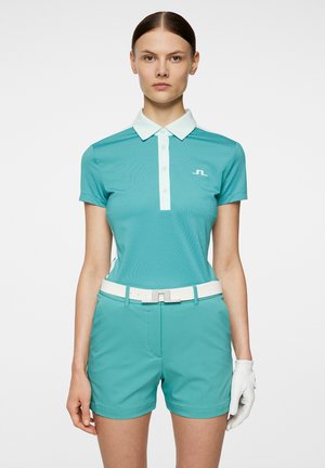 Teal short-sleeve polo shirt with a white collar, paired with teal shorts and a white belt. Features a textured fabric and logo detail.