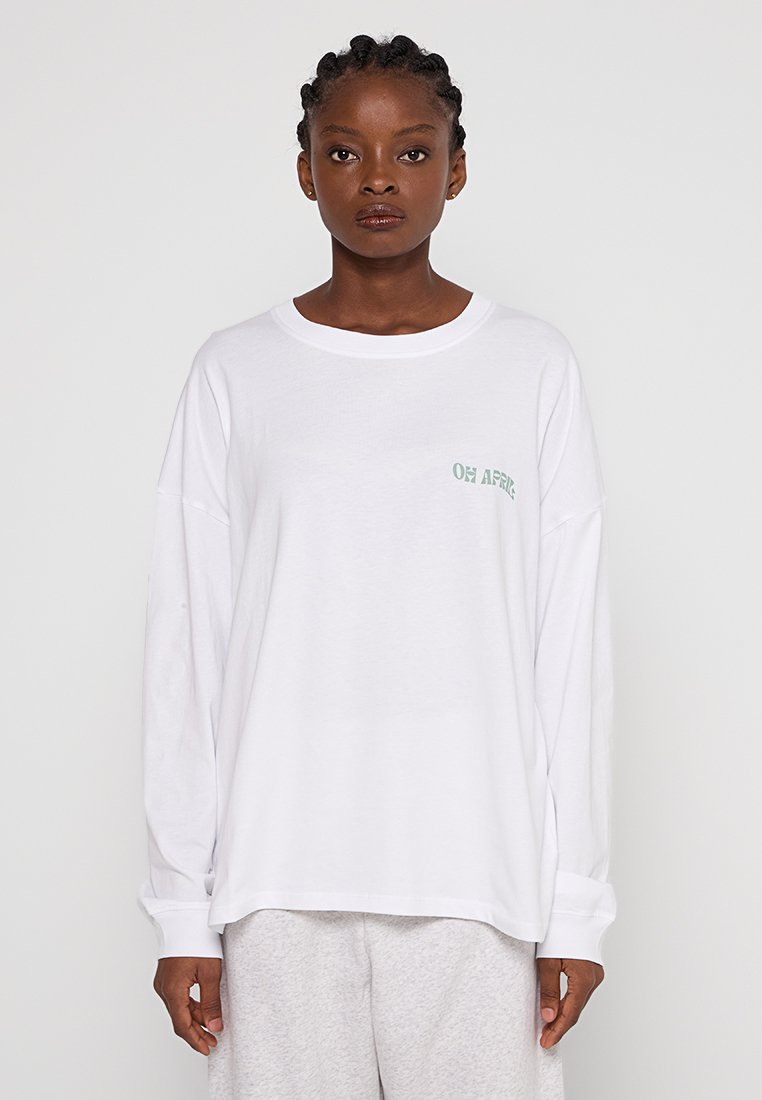 Weißes Langarm-T-Shirt mit grünem Grafikdruck auf der linken Brust, entspannt geschnitten und mit geripptem Rundhalsausschnitt.
