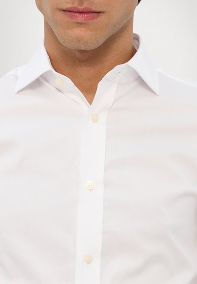 Witte overhemd met knopen, voorzien van een klassieke kraag, kleine knopen en een gladde, licht gestructureerde stof. Geschikt voor formele of casual gelegenheden.