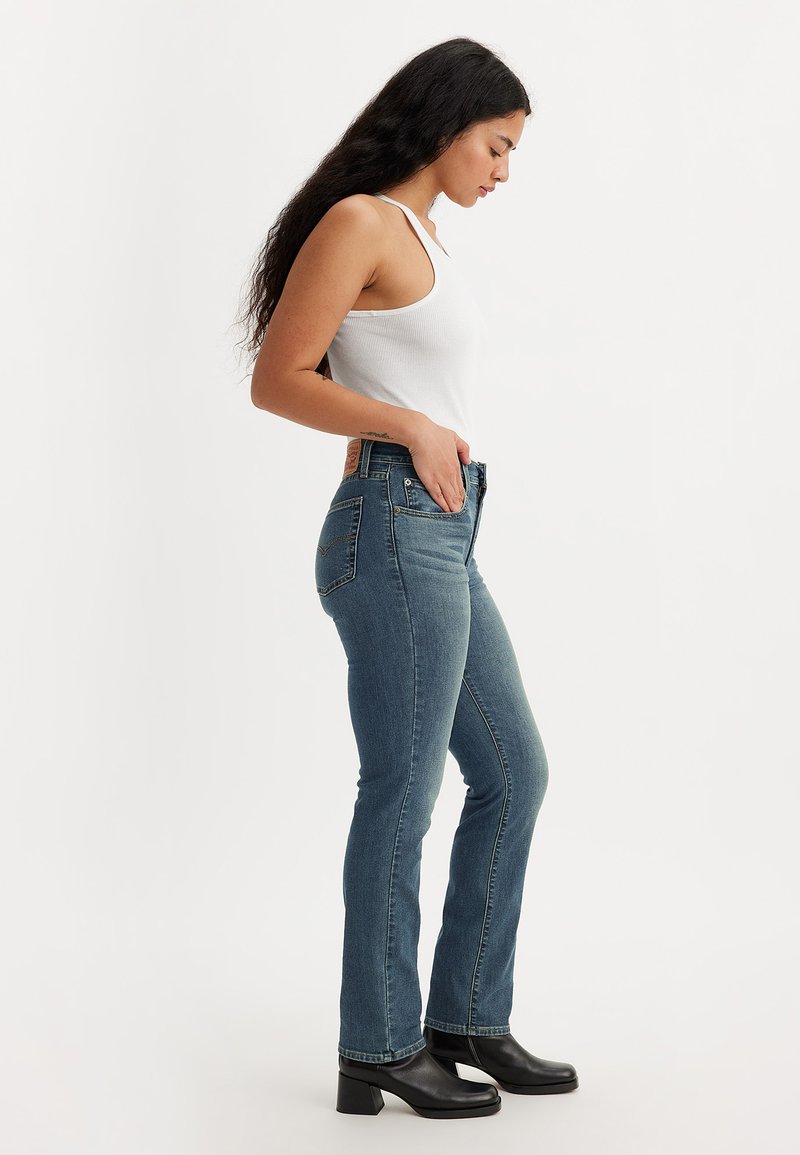 Hochtaillierte blaue Jeans aus Denim mit einer engen Passform, ausgestattet mit einem Reißverschluss vorne, Vorder- und Gesäßtaschen sowie einem Leder-Patch am hinteren Bund.
