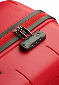 Red hard shell luggage with a textured surface, black zipper and lock mechanism. Includes a TSA-approved lock with three dials.