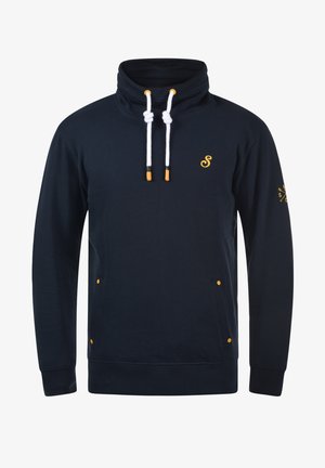 Tengerészkék pulóver magas gallérral, fehér zsinórokkal és narancssárga díszítéssel. Oldalsó zsebekkel és logóval a mellkason és az ujjon.