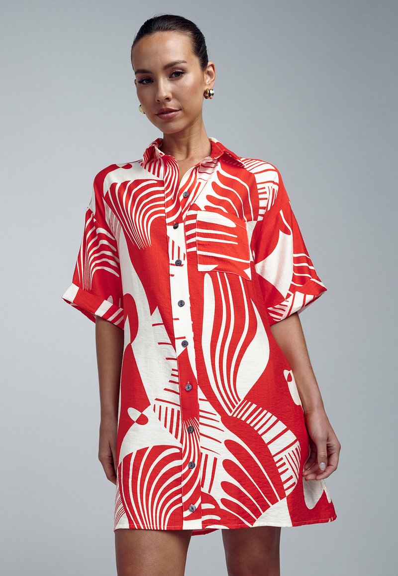 Abito camicia rosso e bianco con un audace motivo astratto, maniche corte, colletto e chiusura con bottoni, realizzato in tessuto leggero.