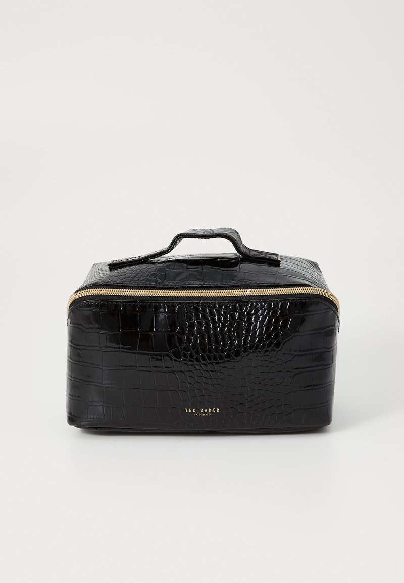 Bolso de maquillaje negro de piel sintética con un patrón de cocodrilo texturizado, cremallera dorada y asa en la parte superior. Presenta el nombre de la marca grabado en la parte frontal.