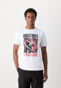 Baltos medvilnės marškinėliai su grafiniu dizainu, turinčiu juodų ir raudonų elementų, tekstais "Guns N' Roses" ir "Use Your Illusion", bei abstrakčiais raštais.
