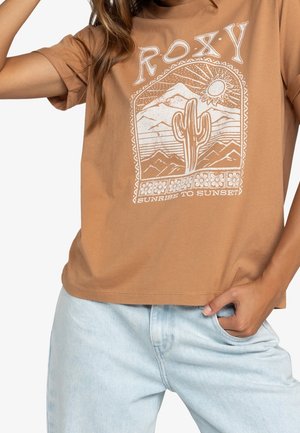 Brązowy bawełniany t-shirt z nadrukiem przedstawiającym góry, kaktusa oraz napis "Od świtu do zmierzchu" w białym kolorze. Luźny krój, krótkie rękawy.