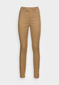 Béžové kalhoty na míru s hladkým povrchem, s bočními kapsami na zip a přiléhavým siluetou. Vysoký pas a rovný střih nohavic.