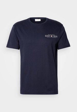 Navy cotton T-shirt featuring a crew neck, short sleeves, and a front print with "GANT 1949" in white. Smooth texture, classic fit.
