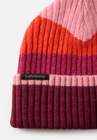 Bonnet en tricot avec des rayures horizontales en orange, rose et violet foncé. Présente une texture côtelée et une étiquette noire avec "PeakPerformance".