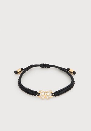 Säädettävä musta punottu rannekoru, jossa on kultasävyinen perhosenmuotoinen koriste, joka on koristeltu pienillä kirkkailla kristalleilla.