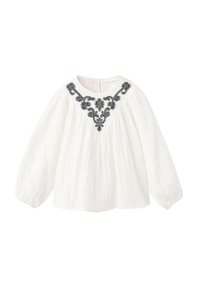 Blouse blanche à manches longues en tissu léger, ornée d'une broderie florale noire le long de l'encolure, avec une coupe décontractée.