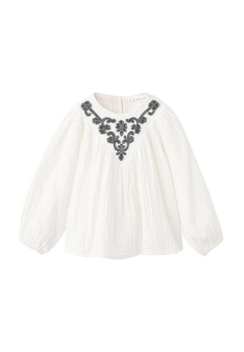 Blouse blanche à manches longues en tissu léger, ornée d'une broderie florale noire le long de l'encolure, avec une coupe décontractée.