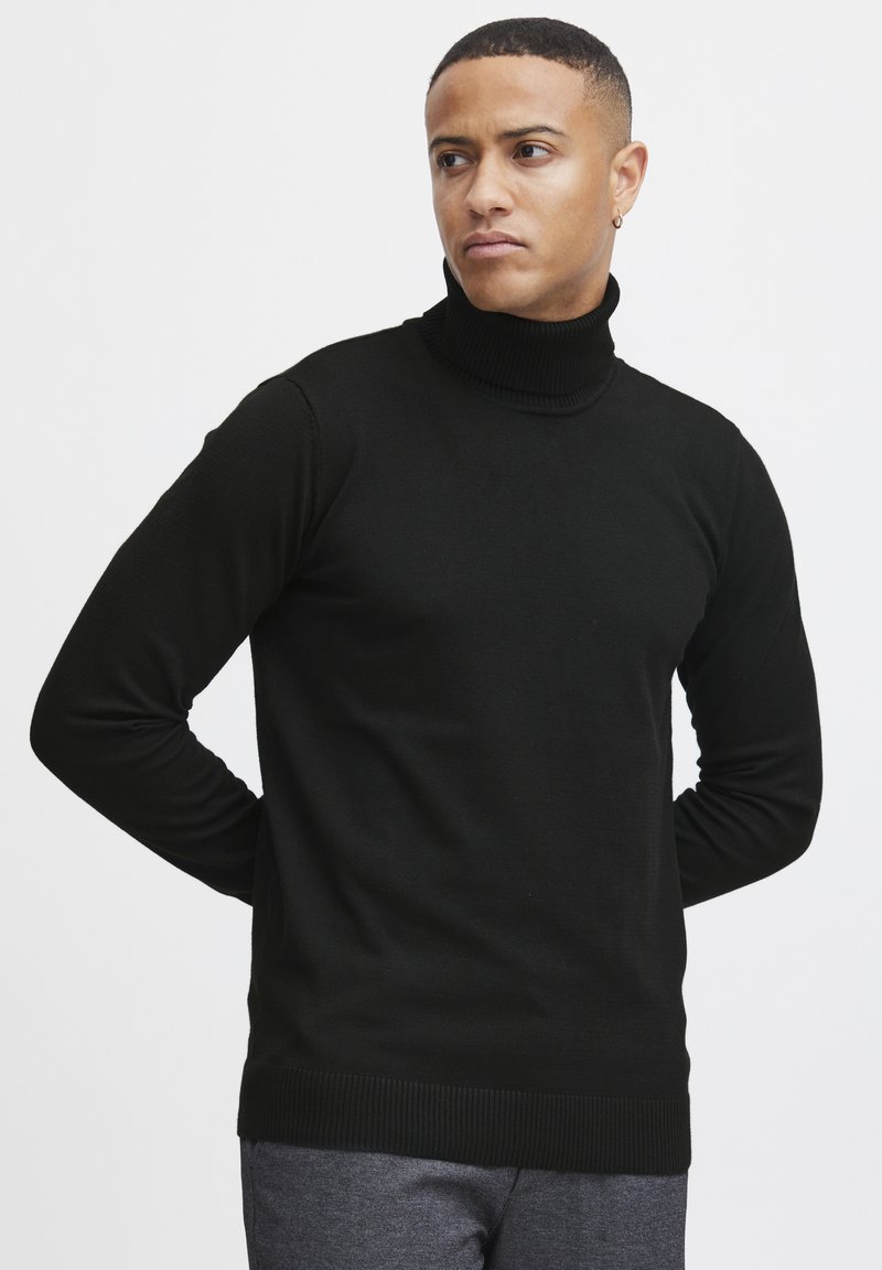 Schwarzer Rollkragenpullover aus glattem Strickstoff. Mit langen Ärmeln und einem gerippten Saum. Einfaches Design ohne Muster oder Akzente.