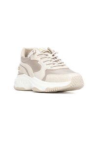 Zapatilla deportiva beige con paneles de malla y sintéticos texturizados, suela de goma blanca y cordones en contraste. Destaca por sus detalles en dorado.