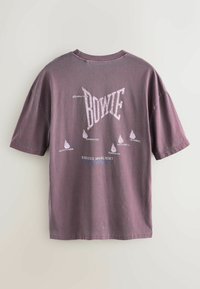 Krótki rękaw, oversize, blada fioletowa koszulka z białym nadrukiem tekstu i miejscami koncertów. Miękki materiał bawełniany o luźnym kroju.
