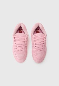 Pink suede sneakers with a low-top design. Features include round laces, perforated toe box, and a red branded insole. Smooth texture.