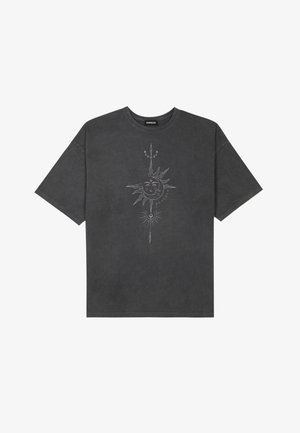 Camiseta de gran tamaño gris oscuro hecha de algodón, con un gráfico central de un sol con intrincados detalles lineales impresos en la parte frontal.