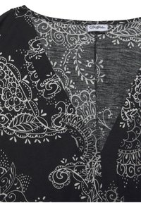 Schwarzer Stoff mit aufwendigen weißen Paisley- und Blumenmustern. Verfügt über einen V-förmigen Ausschnitt und eine weiche Textur. Markenetikett oben sichtbar.