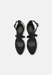 Czarne zamszowe obcasy z wysmukłym noskiem, regulowanymi paskami wokół kostki i gładką podszewką. Miękka tekstura bez widocznych wzorów.