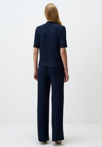 Marineblauwe two-piece outfit met een top met korte mouwen en wijde broek, gemaakt van textuurstof, met een subtiel patroon en rechte snit.