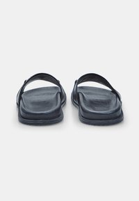 Sandale negre din piele, cu tălpi plate și curele late din material, având o textură netedă și un design minimalist.
