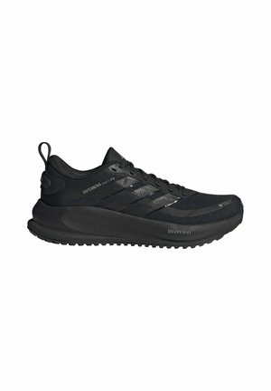 Zapatilla de running negra de Adidas con cordones en la parte delantera, suela gruesa y marcas "Supernova" y "Dreamstrike" en el lateral.
