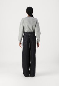 Gray sweatshirt with dropped shoulders, paired with high-waisted, loose-fitting dark denim jeans featuring back pockets and minimal detailing.