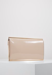 Clutch rectangular de piel sintética beige con acabado brillante, ribete dorado y acento de cadena en el lateral. Textura suave, diseño minimalista.