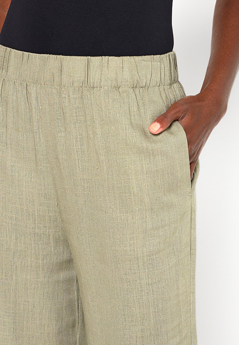 Helle grüne Leinenhose mit elastischem Bund, Seitentaschen und strukturiertem Finish. Der Stoff wirkt weich und leicht.