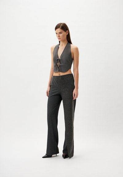 Gray cropped top with V-neck, lacing detail at front. Paired with dark gray, pinstriped, high-waisted trousers featuring side slit, and pointed heels.