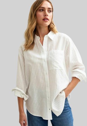 Chemise à rayures blanches à boutons, fabriquée en tissu léger, dotée d'une poche poitrine, de manches retroussées et d'une coupe décontractée. Associée à un jean.