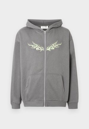 Siva jopa s kapuco na zadrgo z dvema sprednjima žepoma in svetlo zelenim abstraktnim grafičnim motivom v obliki kril čez prsni del in kapuco.