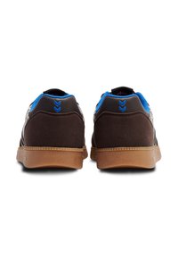 Brązowe buty sportowe z niebieskimi akcentami, z gładką skórzaną i teksturowaną zamszową cholewką, gumową podeszwą oraz chevronowym wykończeniem na pięcie.