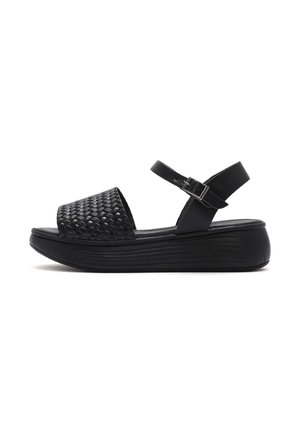 Black platform sandals with a woven texture on the upper, adjustable buckle strap, and a ridged, contoured sole.