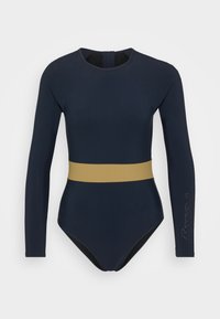 Maillot de bain long à manches navy avec une bande horizontale jaune moutarde à la taille. Texture lisse ; dispose d'une fermeture éclair dans le dos.