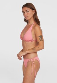 Rožinė bikini maudymosi kostiumėlis su trikampio formos viršumi su surišamomis kaklo juostelėmis ir atitinkančiomis kelnaitėmis su reguliuojamomis šoninėmis raištelėmis, pagamintas iš lygaus elastingo audinio.
