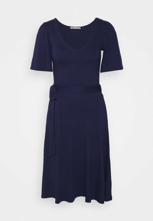 Vestido azul marinho com mangas bufantes curtas, decote em V e laço na cintura. O tecido é suave, com uma saia fluida que atinge a metade da panturrilha.