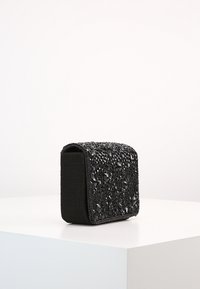 Borsa a pochette nera con superficie texturizzata e decorazioni in perline nere, forma rettangolare e lato in tessuto morbido.