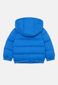 Giacca blu a vento con cappuccio, con sezioni trapuntate e polsini elasticizzati. Tessuto liscio e design leggero per garantire calore.